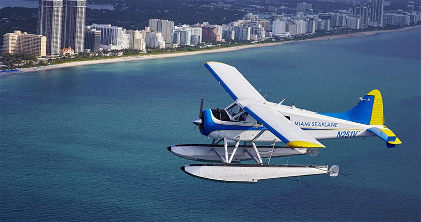 a plane flying over a body of water with a city in the background