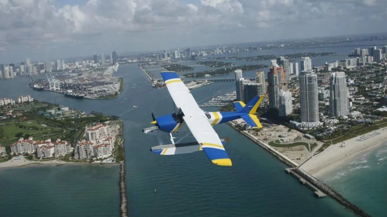  Seaplane flying above Miami skyline, beaches, and turquoise water. 
