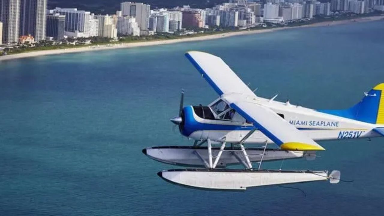 Seaplane flying above Miami skyline with turquoise ocean below.
