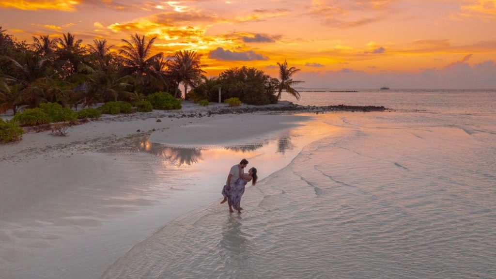 Couple posing on tropical honeymoon beach at sunset glow.