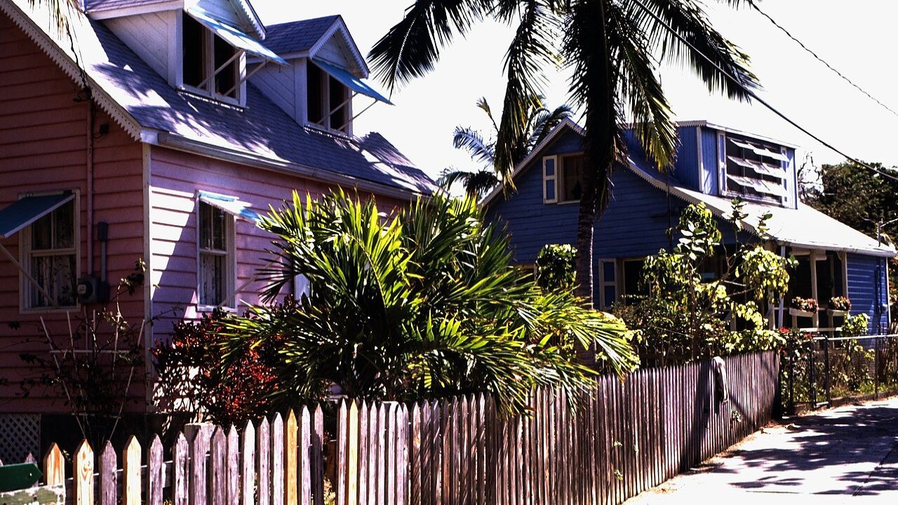 Hope Town pastel cottages with palm tree and picket fence.