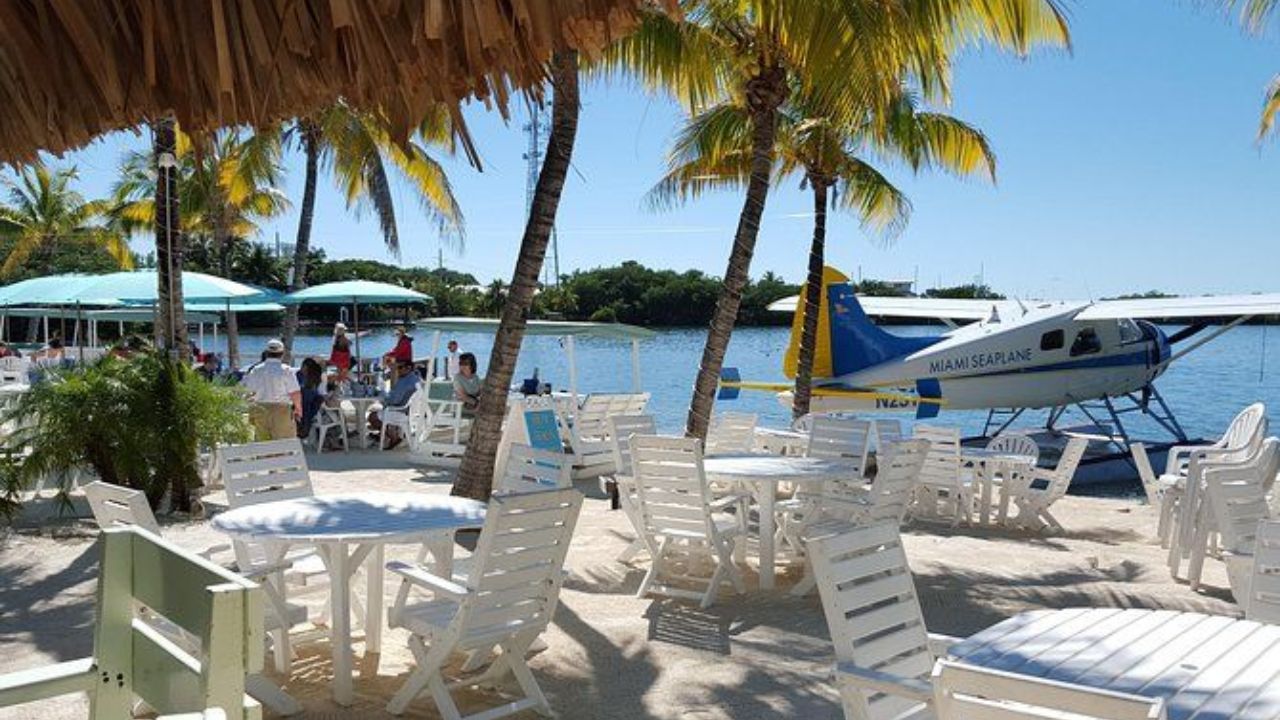 Islamorada waterfront dining with seaplane docked near palm trees.