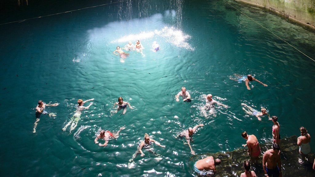 Thunderball Grotto cave with turquoise water and swimmers inside.